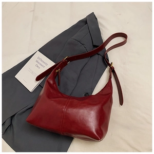 Close-up of deep red hobo bag with vintage oil wax leather on a grey blazer