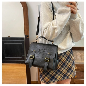 Detail of vintage black leather satchel with double buckles and embossed logo detail