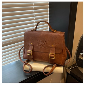 Close-up of vintage brown leather backpack with COIN logo and metal buckle details