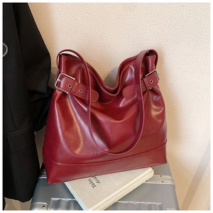 Detail of vintage oil wax leather tote bag with metallic buckles on a silver suitcase