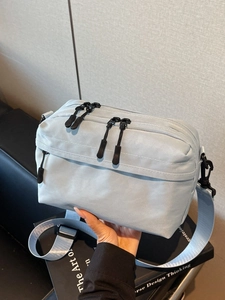 Light blue minimalist nylon crossbody bag with dual zipper compartments and wide strap