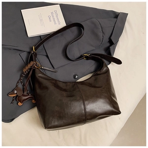 Detail of dark brown leather hobo bag with vintage metal buckle and dachshund charm