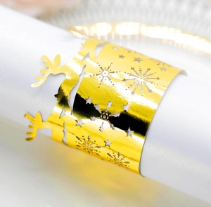 Close-up of golden laser-cut paper napkin ring with elk and snowflake festive patterns