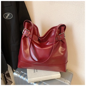 Detail of burgundy large tote bag with silver buckle straps on a luxury luggage setting