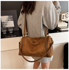 Dettaglio borsa tote in pelle scamosciata marrone con fibbia a cuore dorata e tracolla