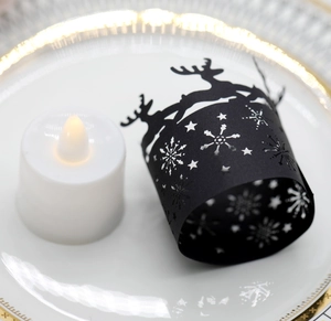 Close-up of black laser-cut paper candle shade with reindeer and snowflake pattern