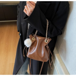 Détail du sac seau marron en similicuir avec chaîne dorée et breloque en peluche