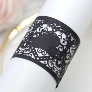 Elegant laser cut black paper napkin ring with intricate scroll patterns for weddings