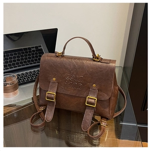 Close-up of vintage brown leather backpack featuring COIN 7NP logo and gold buckles