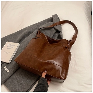 Detail of vintage dark brown oil wax leather tote bag with retro texture and fine stitching