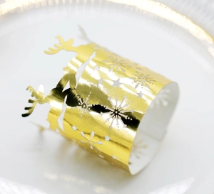 Macro view of gold snowflake and reindeer napkin rings on elegant white ceramic plate
