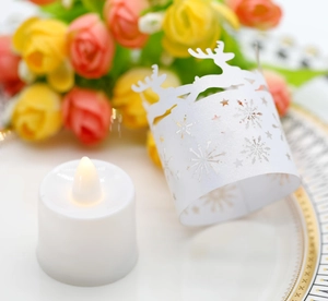 Detail of white laser-cut paper lampshade with deer and snowflakes for LED tealight candle