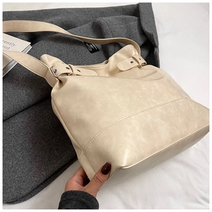 Detail of a beige matte leather bucket bag with an adjustable shoulder strap for women