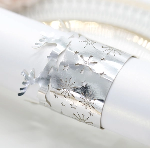 Close-up of laser-cut silver napkin rings featuring reindeer and snowflake patterns