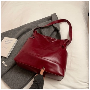 Close-up of deep red vintage oil wax leather tote bag with elegant pleat detail