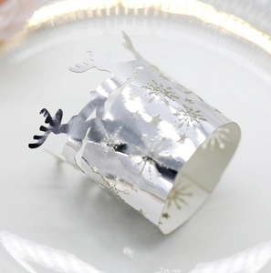 Close-up of laser-cut silver mirror reindeer and snowflake napkin ring on a plate