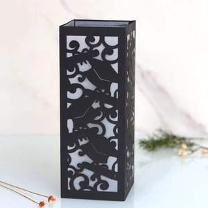 Detail of laser-cut black paper lampshade with elegant scroll patterns for graduation party