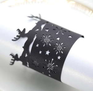 Detail showing matte black laser-cut napkin ring with reindeer and snowflake design
