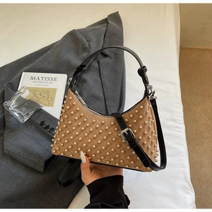 Close-up of vintage brown quilted handbag with white pearl embellishments and black handle