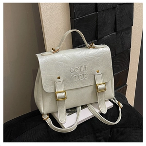 Macro shot of white textured leather backpack with COIN embossing and gold hardware