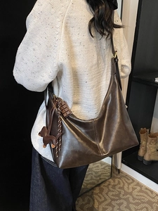 Retro deep brown hobo bag with dachshund charm shown on shoulder in a cozy setting