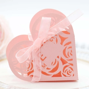 Pink heart-shaped laser-cut wedding favor box with rose patterns and ribbon