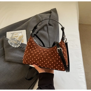 Detail of hobo bag with brown quilted fabric, spherical studs and adjustable black strap