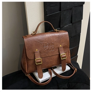 Detail of vintage brown PU leather backpack featuring golden hardware and top handle