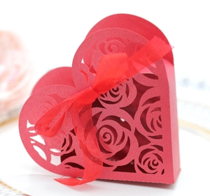 Red heart-shaped candy box with hollow rose pattern and elegant red ribbon for weddings
