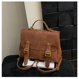 Close-up of vintage brown leather backpack with COIN embossed logo and metal buckles