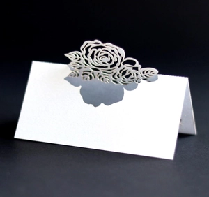 Macro view of laser-cut rose hollow pattern on elegant white folding table place cards