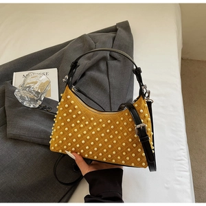 Detail of mustard yellow suede bag with pearl embellishments and black leather strap