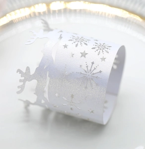 Macro detail of white glitter laser-cut reindeer and snowflake festive paper napkin rings