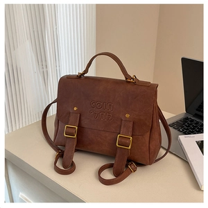 Detail of vintage brown leather satchel featuring COIN embossed flap and gold buckle straps