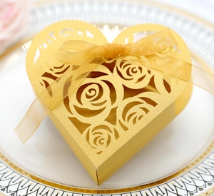 Detail of laser-cut rose patterns on a heart-shaped gold gift box with a silk ribbon