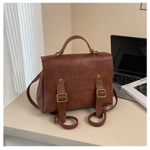 Detail of vintage brown leather backpack with COIN '70D' embossed logo and metal buckle
