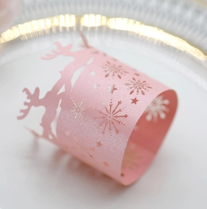 Macro detail of laser-cut pink pearlescent napkin ring with reindeer and snowflake motifs