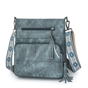 Detail of blue denim crossbody bag with vintage texture and snowflake embroidered strap