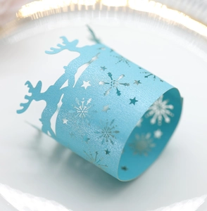 Macro detail of sky blue pearlescent paper napkin ring with reindeer and snowflake cutouts