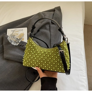 Close-up of green pearl-studded shoulder bag with quilted details and silver hardware