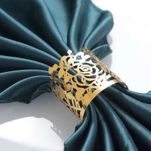 Detail of laser-cut gold rose napkin ring with intricate hollow floral patterns