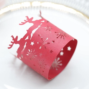 Close-up of red laser-cut snowflake and reindeer napkin ring with festive shimmer texture
