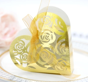 Detail of heart-shaped gold laser-cut favor box with rose patterns and ribbon