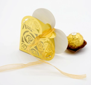 Detail of laser-cut gold rose candy box with an organza ribbon and chocolate accessory