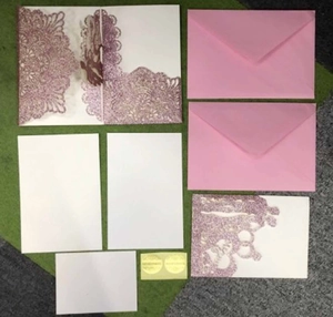 Detailed laser-cut floral wedding invitation set with glitter finish and envelopes