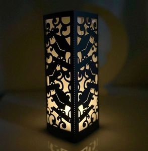 Detailed laser-cut pattern on black lantern with warm glowing light shadow effect