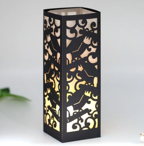 Laser-cut graduation paper lampshade with mortarboard and scroll patterns in warm light