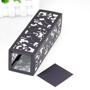 Detailed laser-cut scrollwork on a black decorative paper candle sleeve and gift box