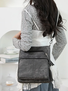 Charcoal grey crossbody bag with vintage leather texture and colorful woven wide strap