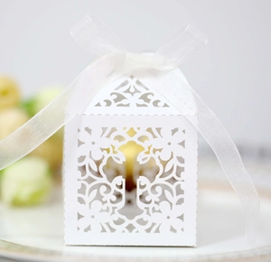 Detailed laser-cut white favor box with cross motif and elegant white chiffon ribbon